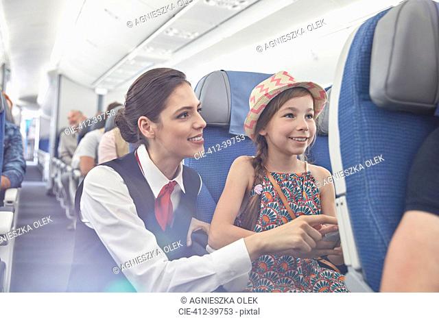 Female flight attendant helping girl on airplane