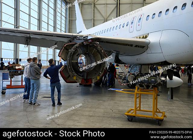 05 February 2023, Rhineland-Palatinate, Hahn: Visitors look at aircraft being serviced in the hangar of the aircraft maintenance company ""Hangar 901""