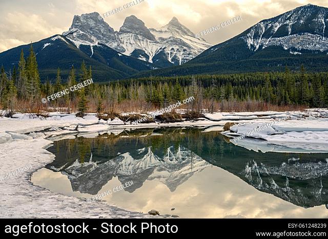 Sunrise over the Three Sisters that is reflecting in the snowy, icy Policeman Creek, Canmore, Alberta, Canadian Rockies, Canada