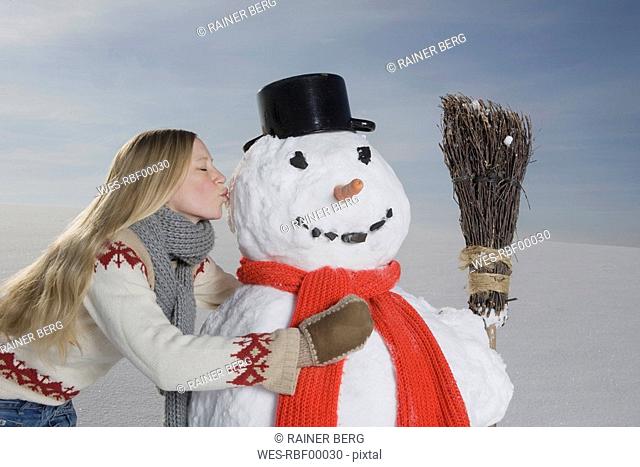Germany, Bavaria, Munich, Young Woman Kissing Snowman, portrait