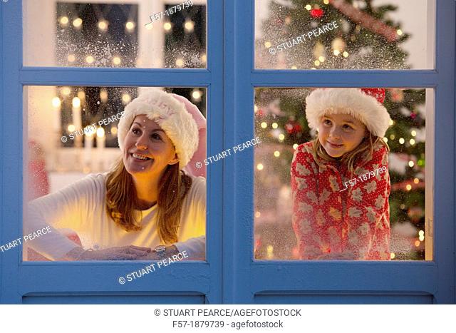 Mother & daughter looking out of the window waiting for Santa to arrive