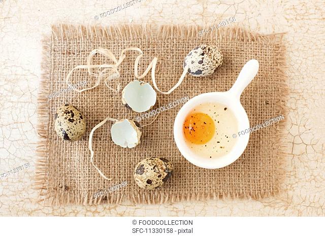Three whole quail's eggs with a cracked open egg and shells