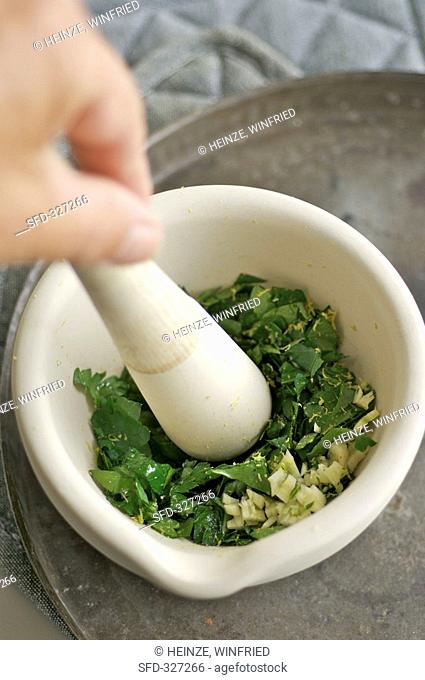 Crushing parsley and garlic in a mortar for pesto