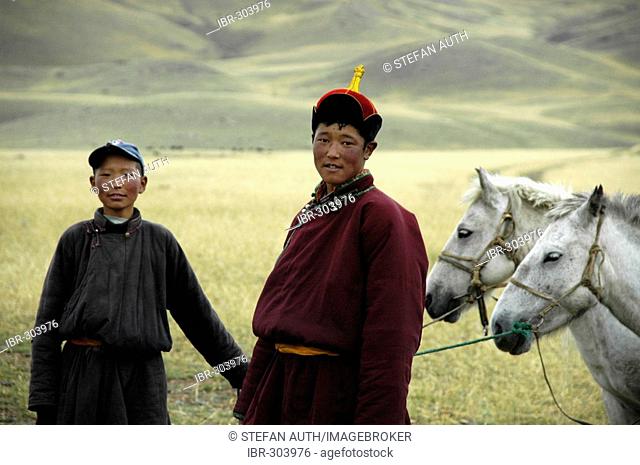 Portrait nomads two shepherd boys dressed in traditional coat and hat are standing with their horses in the steppe Kharkhiraa Mongolian Altai near Ulaangom Uvs...