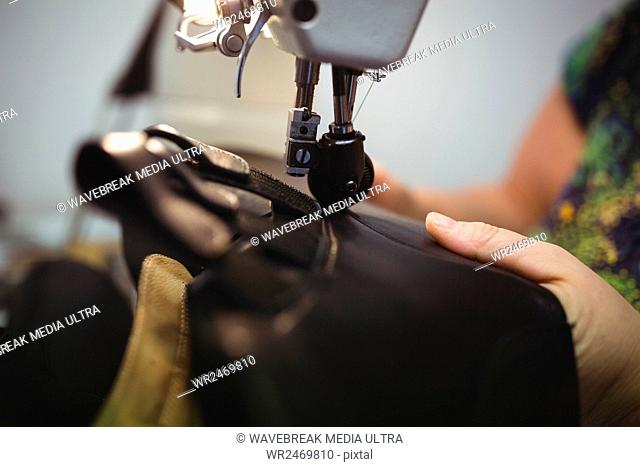 Close-up view of a cobbler using a sewing in a workshop