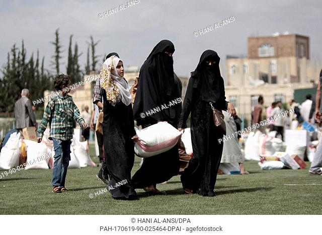 Yemenite women carry bags of grain they received as part of an aid donation by the government of Kuwait in Sanaa, Yemen, 19 June 2017