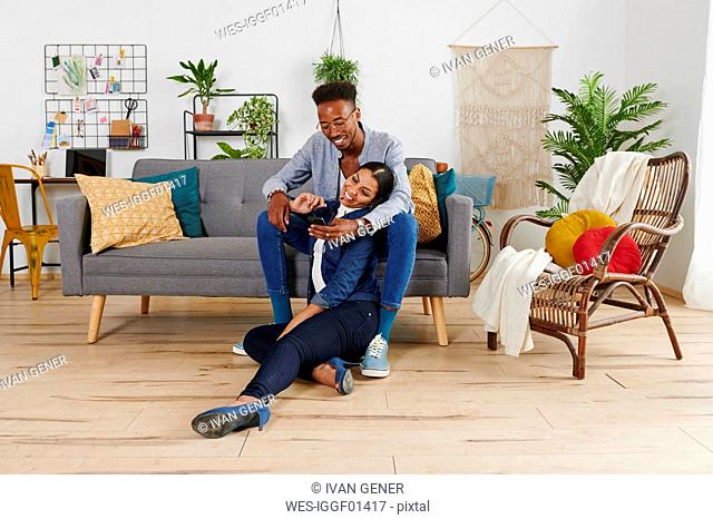 Multiethnic couple spending time together at living room, taking a selfie