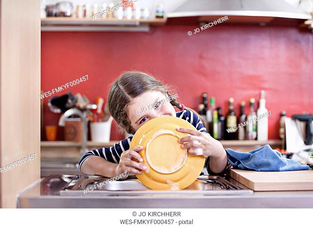 Germany, North Rhine Westphalia, Cologne, Girl washing plates in kitchen sink, close up