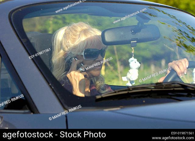 Junge Frau telefoniert beim Auto fahren
