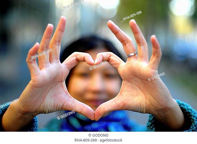 Woman making a heart with her fingers, Paris, France, Europe