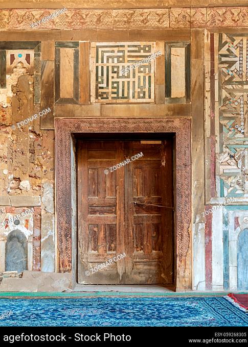 Grunge wooden decorated door on external old decorated marble wall, El Mardani Mosque, Cairo, Egypt