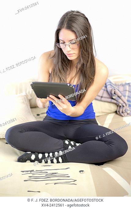 Young Woman relaxing on her sofa with her tablet