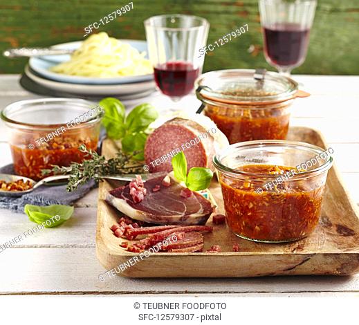 Bolognese sauce in preserving jars served with Parma ham and salami
