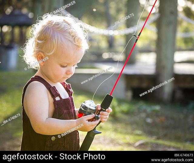 Cute young boy with fishing pole outside at the lake