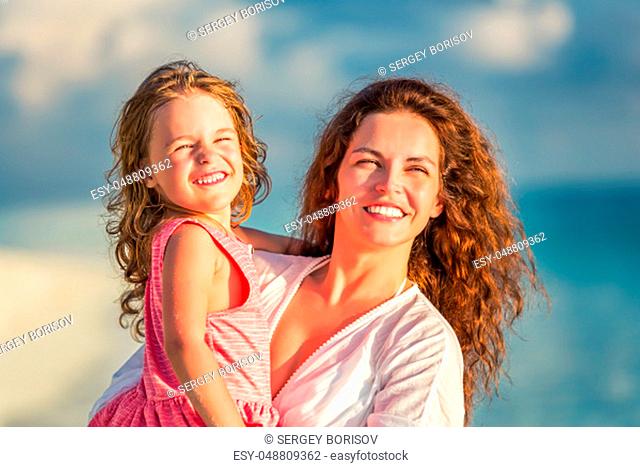 Portrait of happy mother and little daughter on sunny beach on Maldives at summer vacation