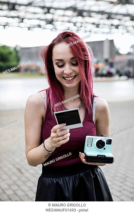 Happy young woman with instant camera and photo outdoors