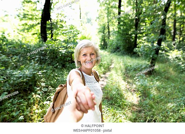 Portrait of happy senior woman holding man's hand in nature