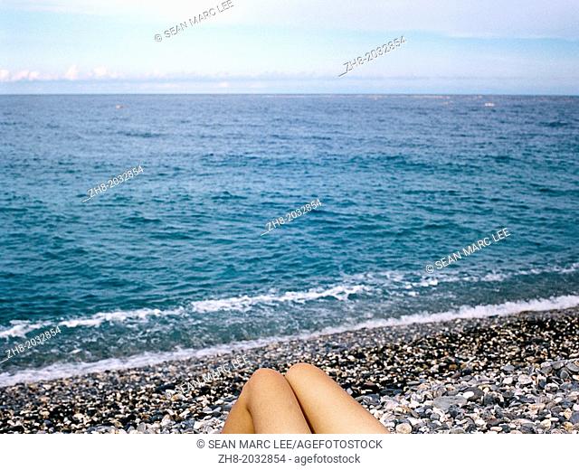 A woman's legs leisurely looking out on a rocky beach at Chi Shing Tan beach in Hualien, Taiwan