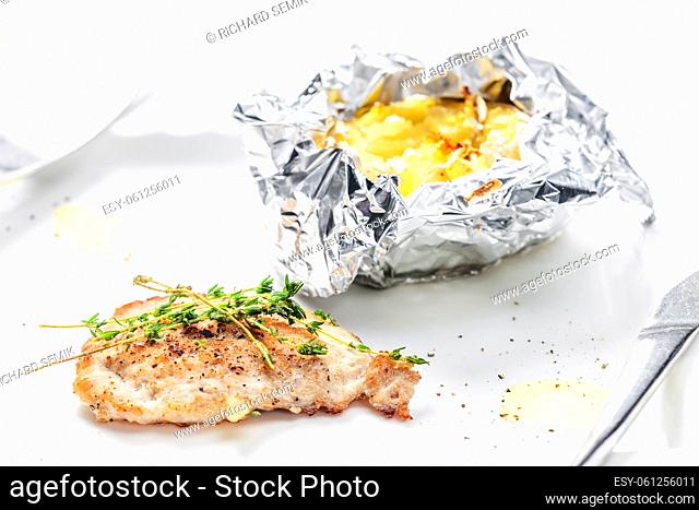 poulry steak with baked potato in aluminum foil