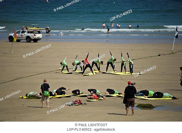 England, Cornwall, Newquay, Surfers warming up on the beach at a surf school at Towan beach, Newquay