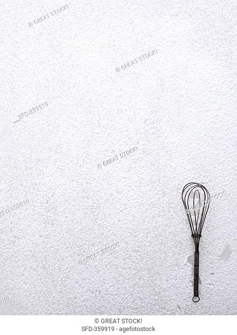 A whisk on icing sugar