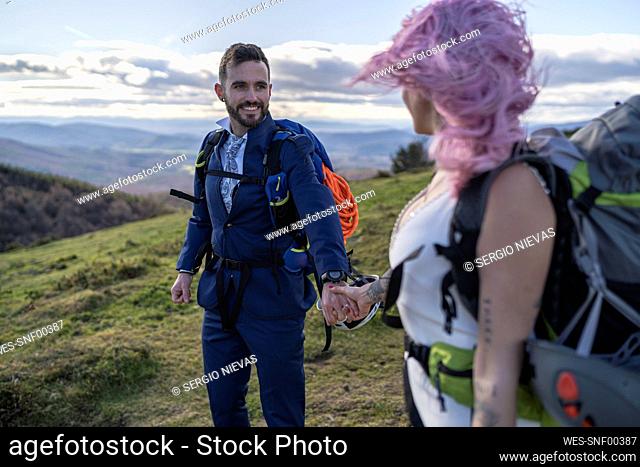 Bridal couple with climbing backpacks in front of Urkiola mountain, Spain