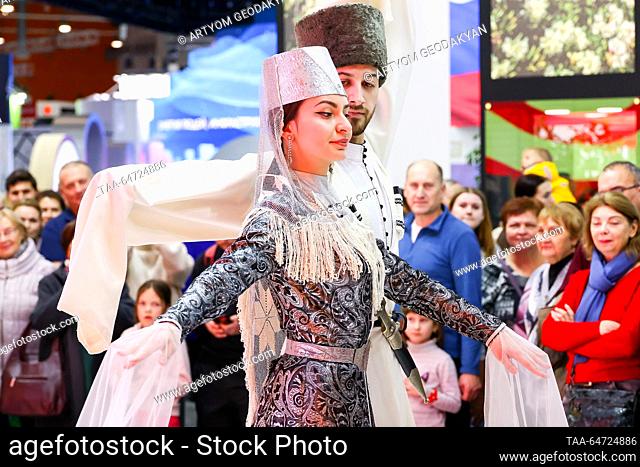 RUSSIA, MOSCOW - 12 de NOVIEMBRE, 2023: Una mujer y un hombre con traje tradicional realizan un baile folclórico en un stand de la República de Ossetia-Alania...
