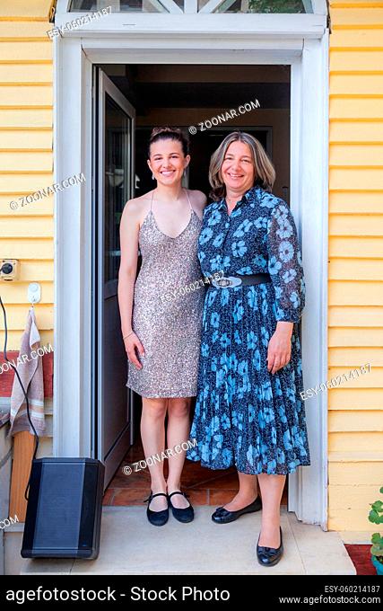 Happy Teenager Graduated from school is standing on the porch smiling with her proud mother