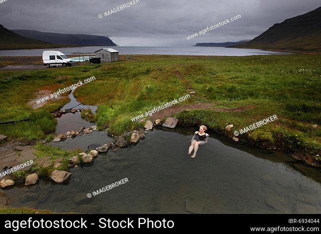 Natural pool at fjord, hot pot, geothermal spring, woman bathing Reykjafjarðarlaug, Vestfirðir, Westfjords, Iceland, Europe