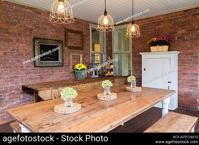 Pinewood table and sitting benches plus old workshop bench and white wooden armoire in veranda at the back of an old 1900 Victorian Queen Anne revival style...