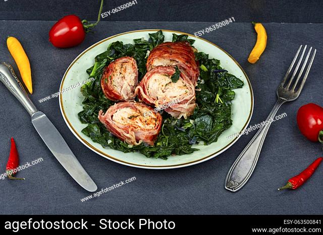 Baked chicken roll with fried spinach leaves. Space for text