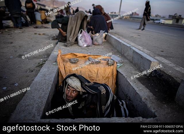 09 November 2022, Afghanistan, Kabul: Afghan men smoke drugs while sitting in a sewer on the side of a road in Kabul. Drug addiction has been a long standing...