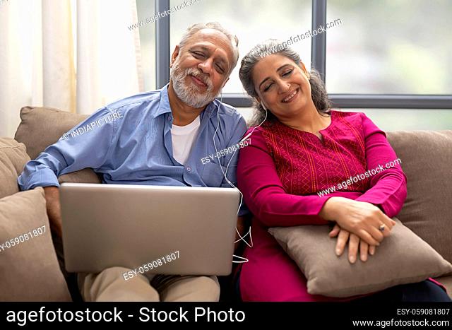 A HAPPY OLD COUPLE LISTENING TO MUSIC ON LAPTOP