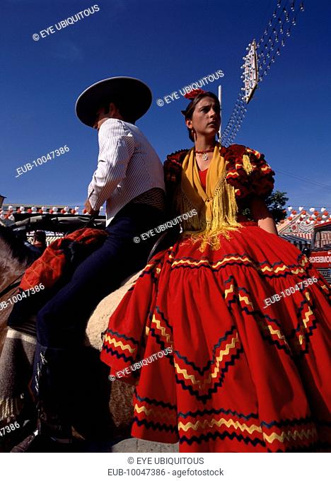 Couple in Flamenco costume riding horseback at the April Fair in Los Remedios district