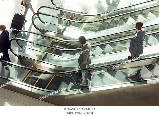 Business people using escalators in modern office