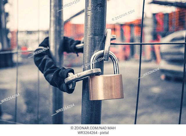 chain and padlock on gate at construction site - lock on closed fence