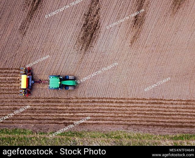 Russia, Aerial view of tractor plowing brown field