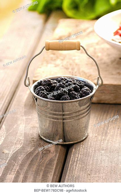 Blackberries in silver bucket on wooden rustic table