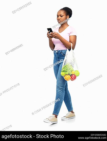 woman with smartphone and food in string bag