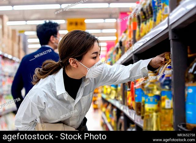 The young couple wearing a mask in the supermarket shopping