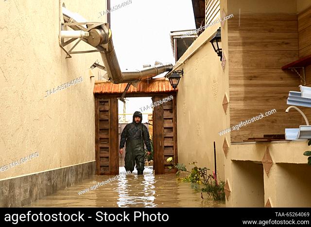 RUSSIA, YEVPATORIA - NOVEMBER 27, 2023: A man wades through the water in the backyard in a submerged section of Simferopolskaya Street during a flash flood