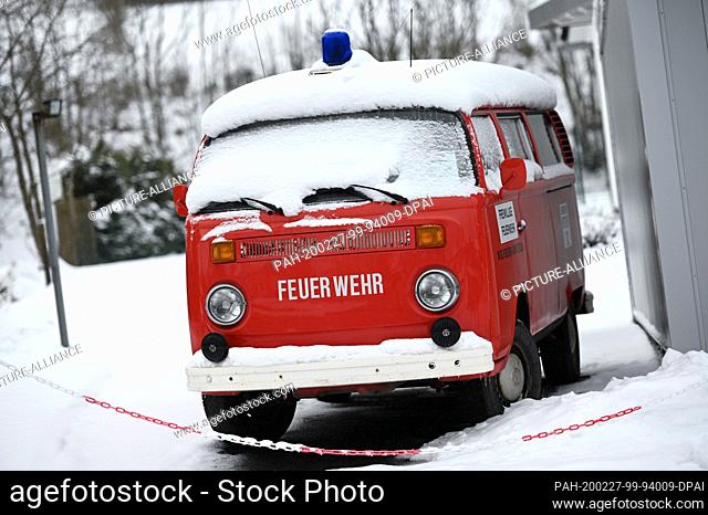 27 February 2020, Hessen, Usseln: A snowed-in old VW van with a fire brigade livery stands in front of a vintage car shop specialising in old Volkswagen cars