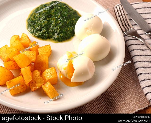 Organic spinach served with spicy potato cubes and boiled organic egg on a white plate. Healthy food
