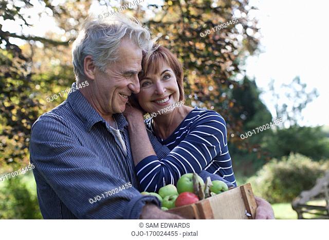 Happy senior couple with bushel of apples hugging