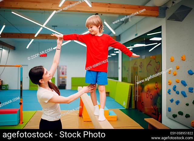 Kids doing balance beam gymnastics exercises in gym at kindergarten or elementary school. Children sport and fitness concept