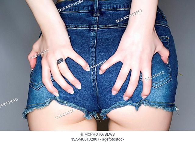 Young woman wearing jeans hotpants pinching her bottom