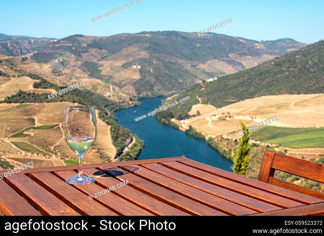Glass of white wine for tasting above the hillsides of the Douro valley in Portugal