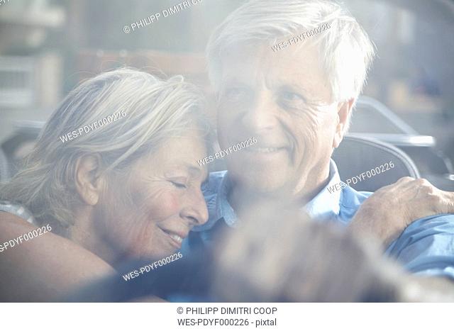 Spain, Senior couple behind glass window, smiling