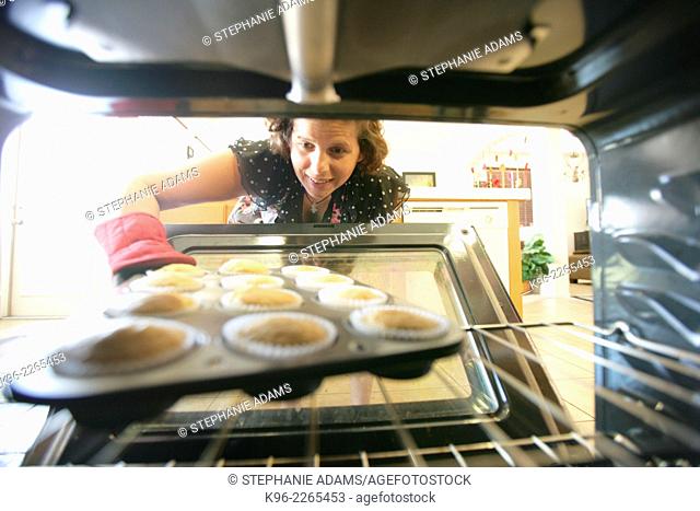 Looking out from inside the oven as a woman pulls out freshly baked cupcakes