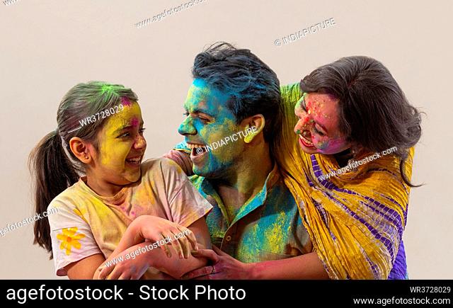 Daughter getting tickled by her parents while celebrating Holi